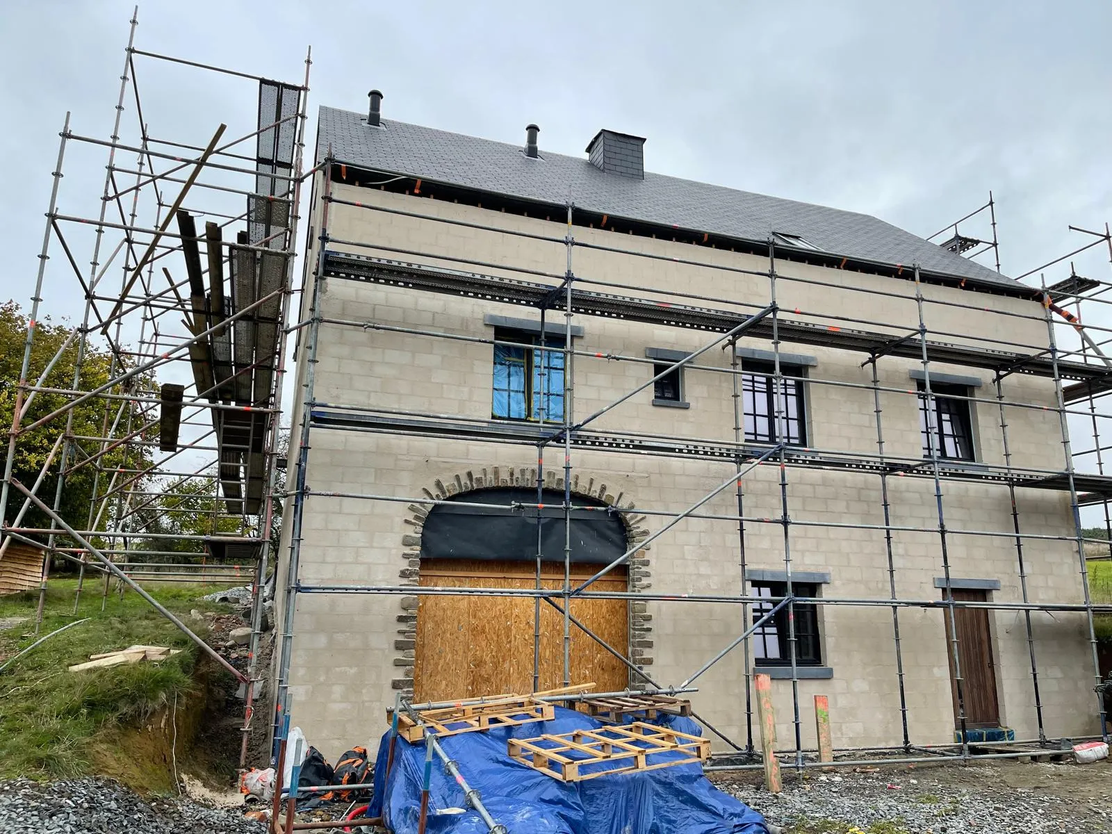 Maison rurale avant restauration — façade brute en blocs, échafaudage installé