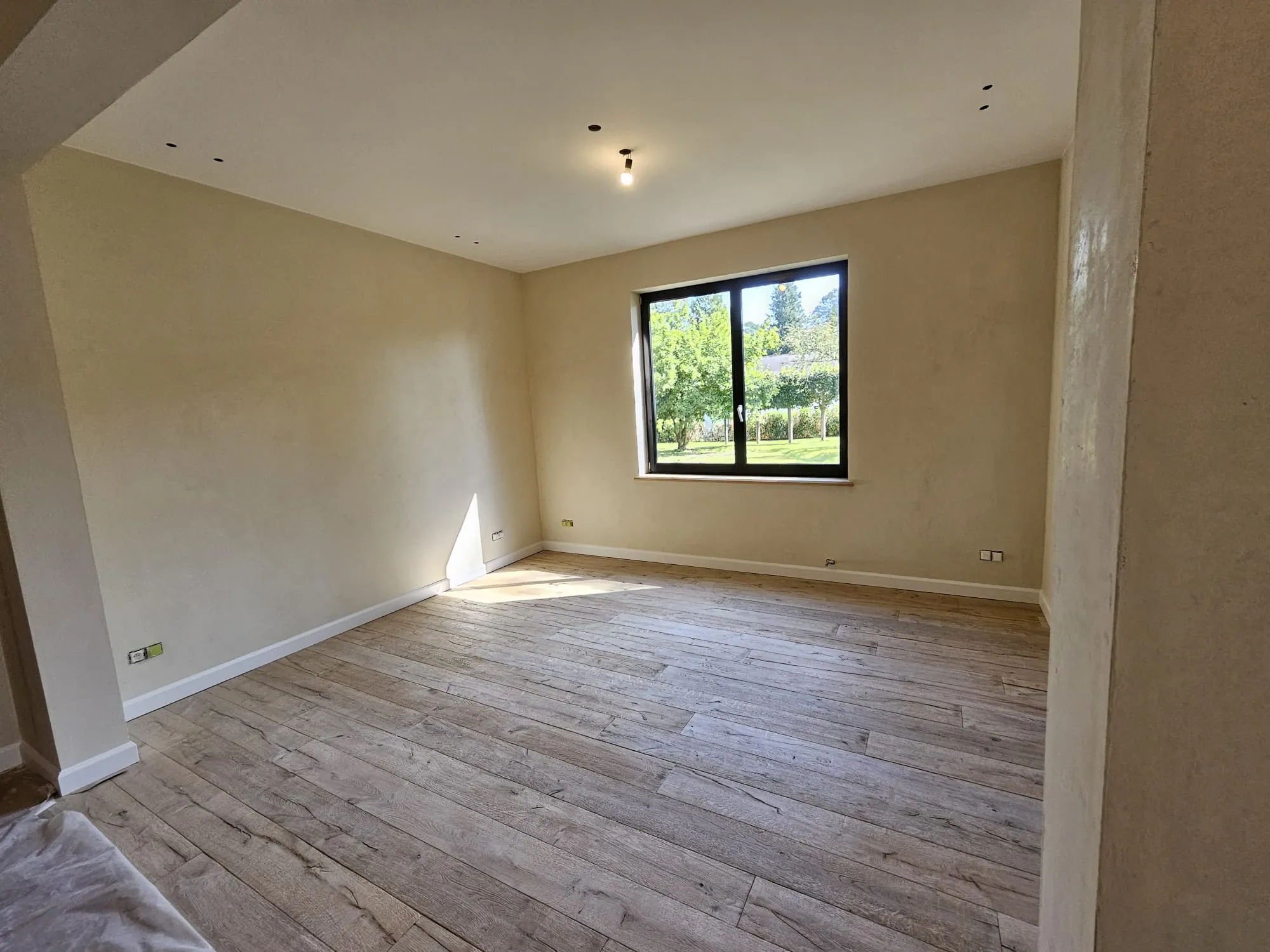 Salon fini avec enduit à la chaux teintée jaune, parquet en chêne brossé et menuiserie noire