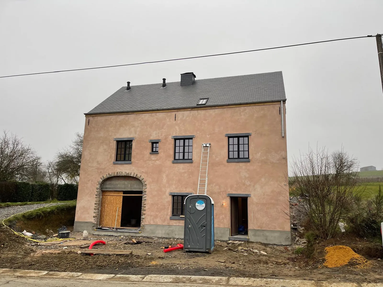 Maison en cours de restauration — première couche d'enduit terracotta sur la façade