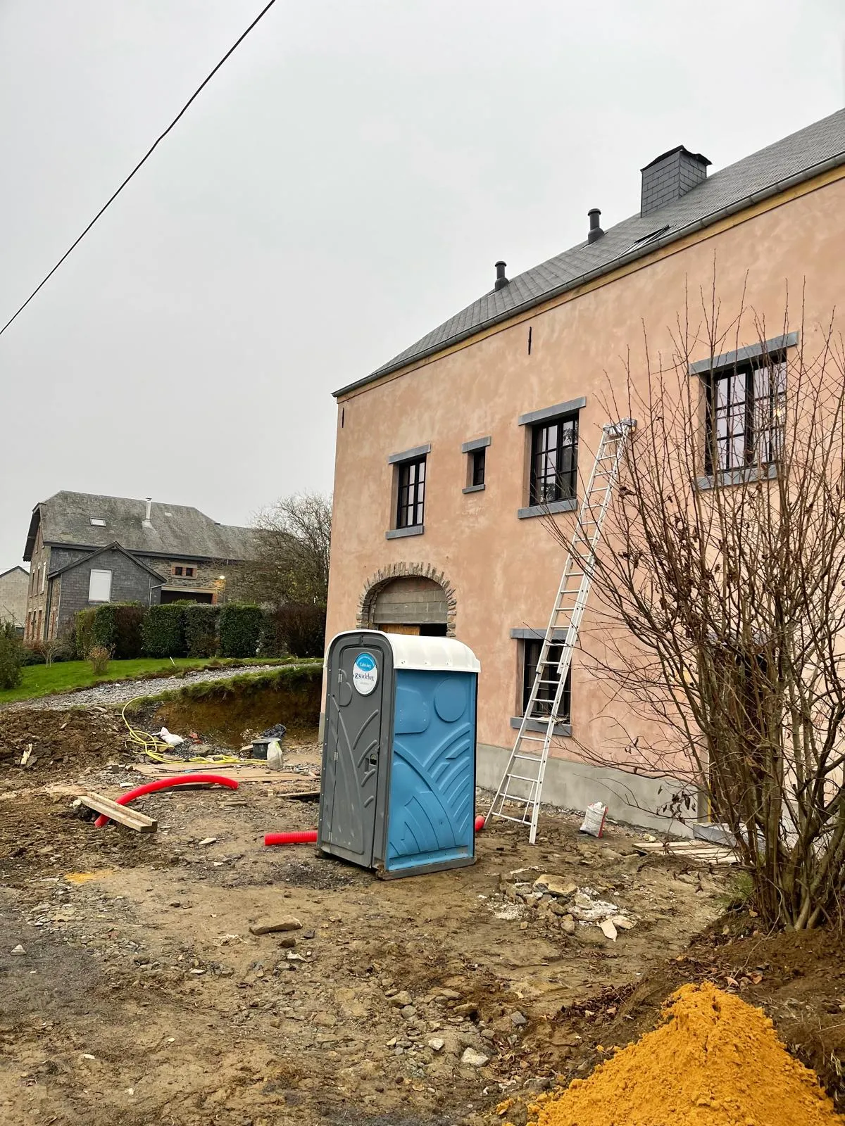 Vue de côté de la maison en travaux, dépendance voisine en arrière-plan