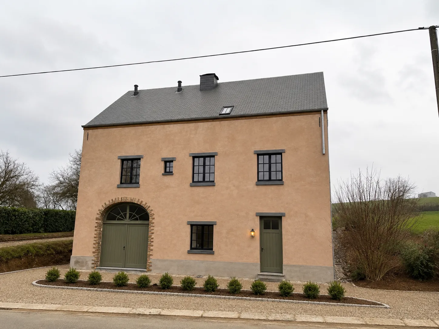 Maison rurale restaurée — façade en enduit terracotta naturel, menuiseries vert sauge, jardin réaménagé